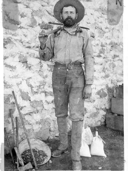 Fred Hamilton (son of Ezra Hamilton) in mining clothes and surrounded by the tools of his trade,