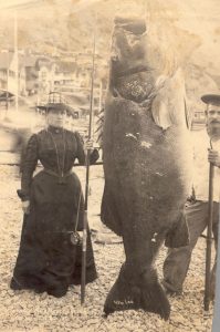 Mrs. A.W. (Pauline) Barrett and boatman Jim Gardner with the black sea bass she had caught, 1901