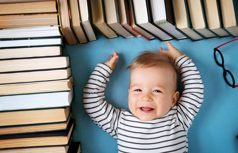 baby laying down surrounded with books