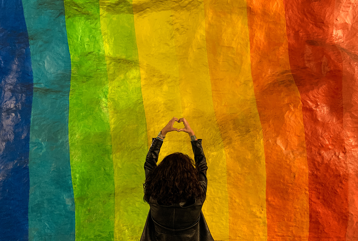 Rear View Of Woman Making Heart Shape While Standing Against Multi ...