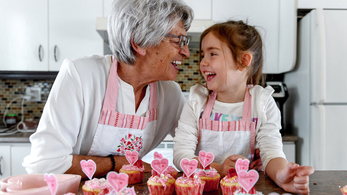 Child and grandmother making cupcakes for Valentine's Day