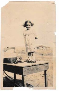 Mary Ethel King (1930-2014), daughter of Mary Prioleau and Ralph King, first Prioleau grandchild, standing on a table with Prioleau. Manhattan Beach cottage in the background, circa 1932. From the files of Mary King, courtesy of the Prioleau-King family.