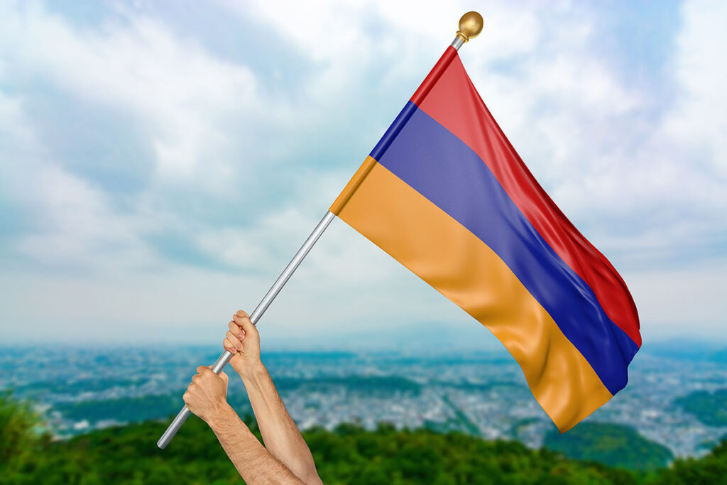 Hands holding a flagpole with the Armenian flag