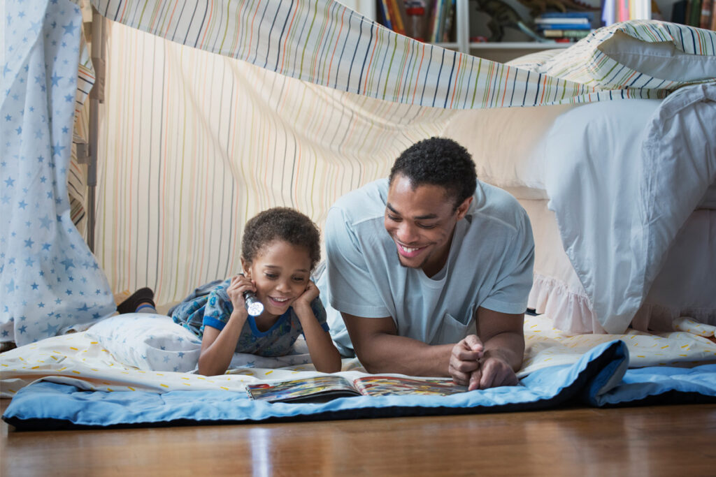 Man and boy reading together in an inside fort