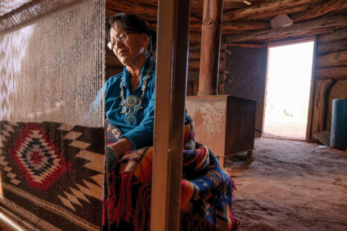 Indigenous woman weaving a colorful blanket