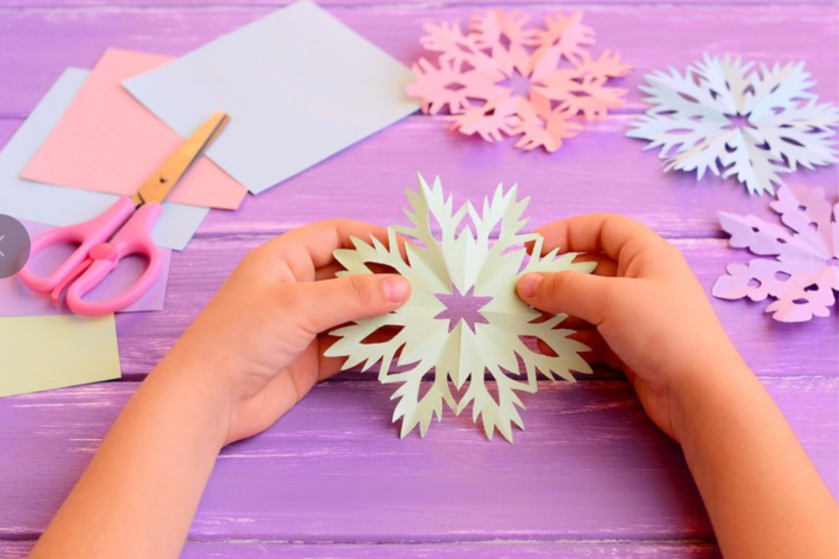 child holding a home made paper snowflake