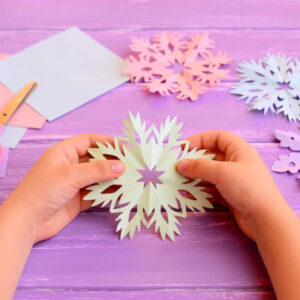 Child holding a handmade paper snowflake