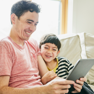 Father and son happily reading on tablet.