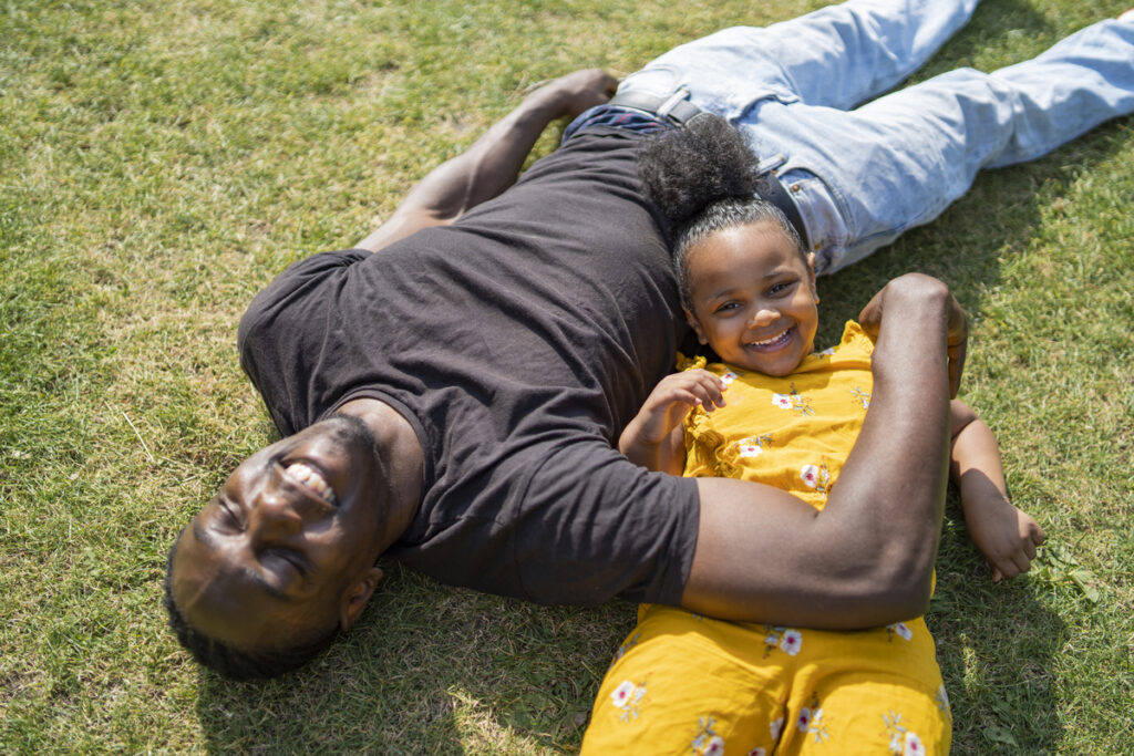 father and daughter lying in the grass