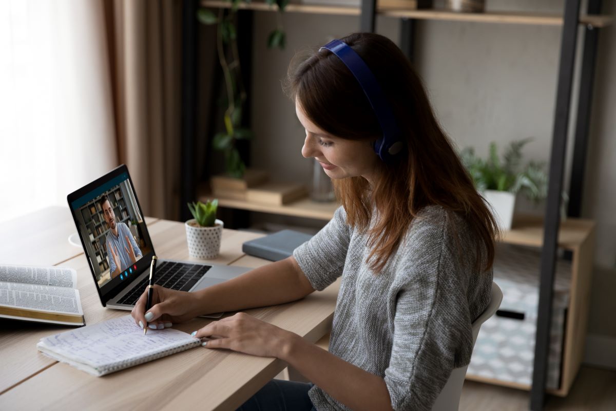 Woman watching a webinar taking notes