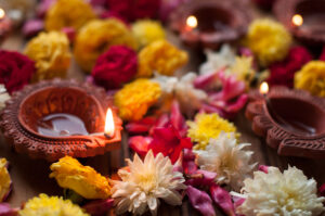 Lamps lit during Diwali celebration with flowers and sweets in background