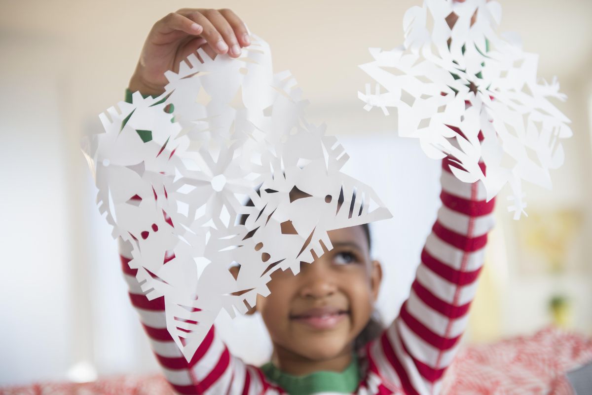 child holding paper snowflakes