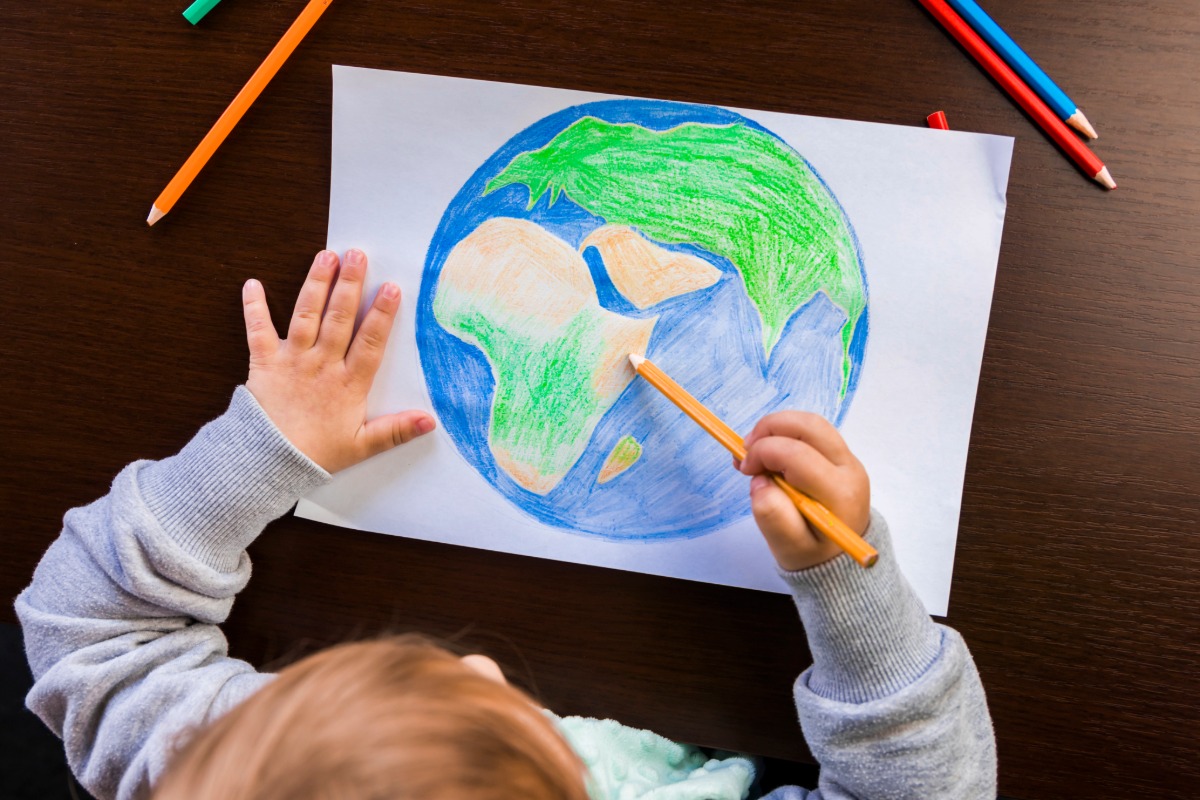 child drawing the earth with colored pencils