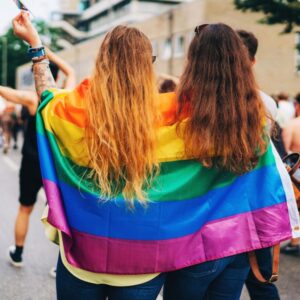 couple with a pride flag draped over their shoulders