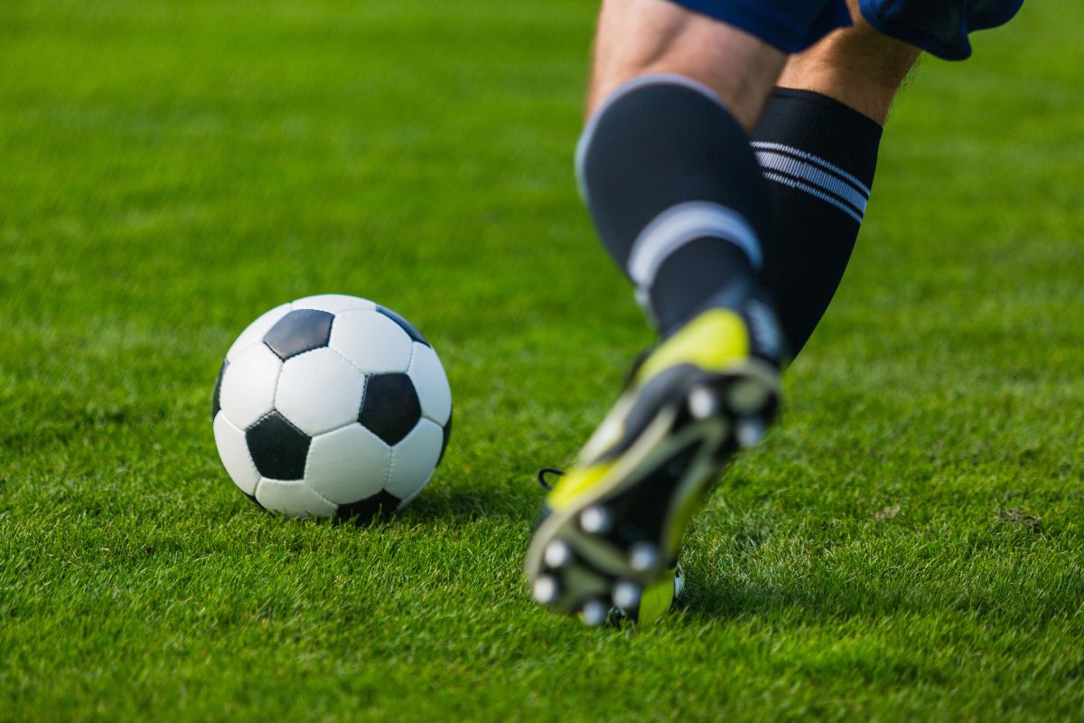 feet of a soccer player kicking the ball